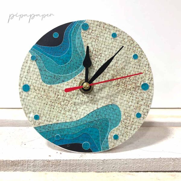 reloj sobre mesa de papel reciclado hecho a mano